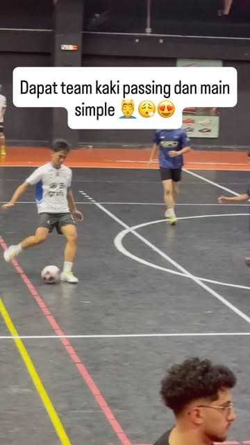 A player in white strikes a pass during a futsal session